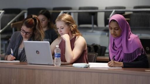 three students taking notes during class